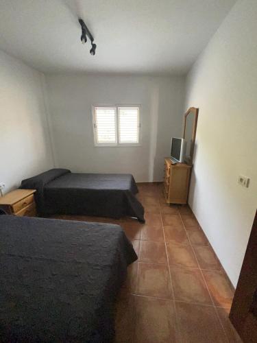 Un dormitorio con dos camas y un televisor. en Casita con piscina privada, en Igueste