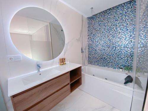 een badkamer met een wastafel, een bad en een spiegel bij Apartamento exclusivo en la playa in Denia