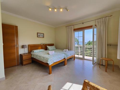 a bedroom with a bed and a large window at Vila Limoeiro in Salir de Porto