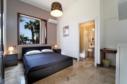 een slaapkamer met een blauw bed en een raam bij B&B Kòre in Castellammare del Golfo