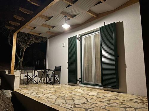 a patio with a table and chairs and a window at The Old Stables Apartment in Vátos
