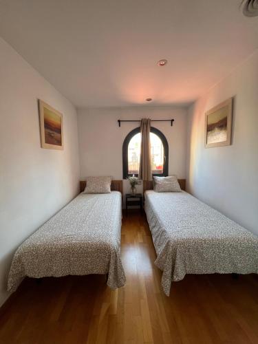 2 camas en una habitación con ventana en CASA NEUS, casa junto a Barcelona, en Sant Feliu de Llobregat