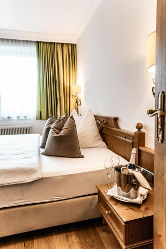 a bedroom with a bed with a table with a tray of wine glasses at Hotel Hubertushof in Anif