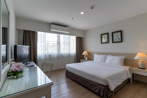 a hotel room with a bed and a television at Classic Kameo Hotel and Serviced Apartments, Sriracha in Si Racha