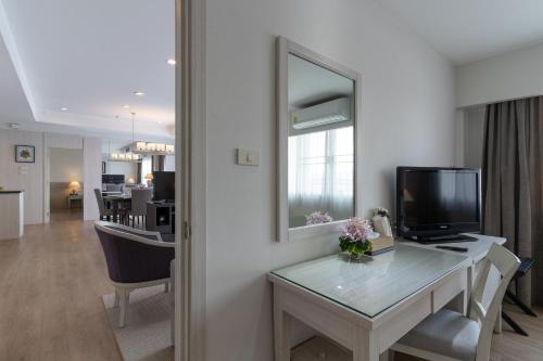 a room with a desk with a tv and a mirror at Classic Kameo Hotel and Serviced Apartments, Sriracha in Si Racha