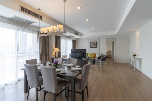 a dining room and living room with a table and chairs at Classic Kameo Hotel and Serviced Apartments, Sriracha in Si Racha
