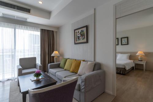 a living room with a couch and a room with a bed at Classic Kameo Hotel and Serviced Apartments, Sriracha in Si Racha