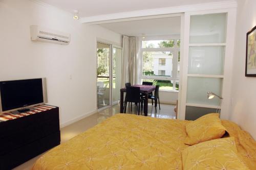 a bedroom with a bed and a television and a table at Green Park en Punta del Este in Punta del Este
