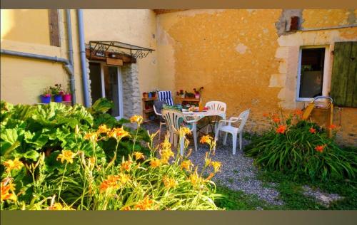 un patio con mesa, sillas y flores en Le refuge, en Ceton