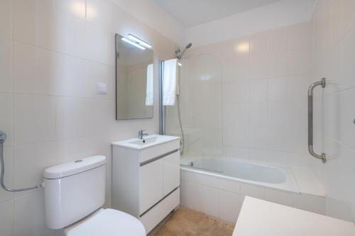 une salle de bain blanche avec toilettes et baignoire dans l'établissement Casa dos Amigos, à Alvor