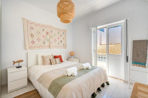 une chambre blanche avec deux lits et une fenêtre dans l'établissement Casa dos Amigos, à Alvor