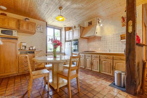 une cuisine avec des armoires en bois et une table et des chaises dans l'établissement La Maison du Meunier, à Cercy-la-Tour