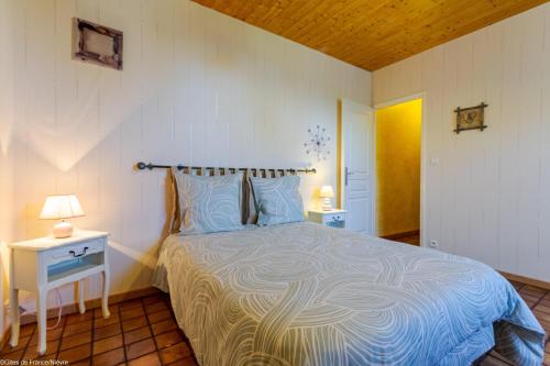 Cercy-la-TourにあるLa Maison du Meunierのベッドとランプ付きのテーブルがある寝室