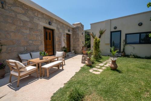 a patio with a table and chairs in a yard at Cavos Luxury Apartments in Kissamos