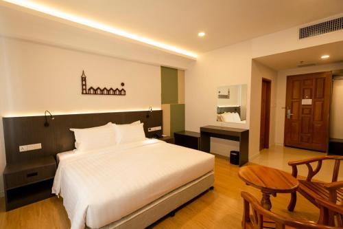 ein Schlafzimmer mit einem Bett und einem Schreibtisch in einem Zimmer in der Unterkunft Havana Hotel Mandalay in Mandalay