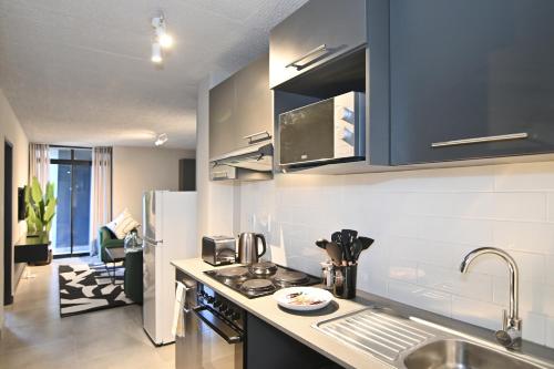 a kitchen with a sink and a refrigerator at Circa Aparthotel by Totalstay in Pretoria