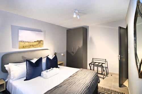 a bedroom with a large bed with blue pillows at Circa Aparthotel by Totalstay in Pretoria