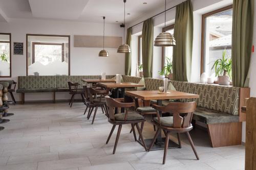 a restaurant with tables and chairs and a bench at Hotel Bergland in Cadipietra