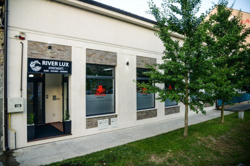 a building with windows and a tree in front of it at Mini Hotel RiverLux Apartments in Bačka Palanka