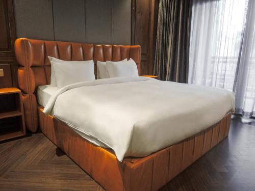 ein großes Bett in einem Zimmer mit einem Kopfteil aus Holz in der Unterkunft CHECK inn Phnom Penh BKK1 in Phnom Penh