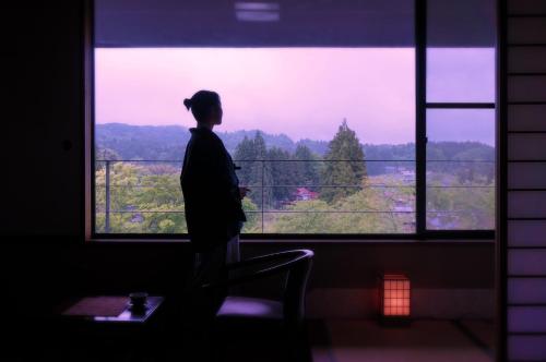 a person standing in front of a large window at 厳美渓温泉いつくし園 in Itsukushi