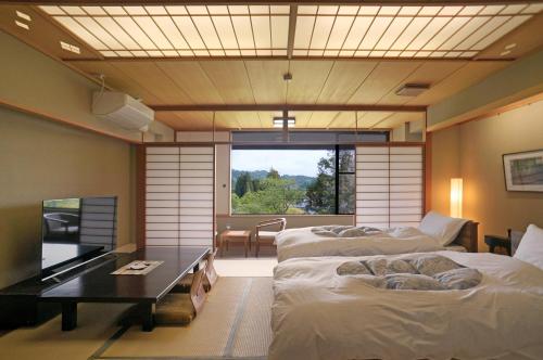 a room with two beds and a table and a window at Itsukushien 
