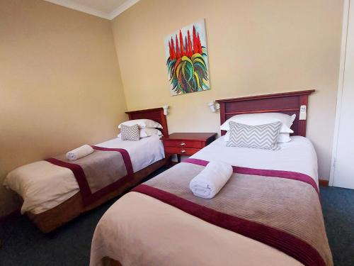 a hotel room with two beds and a painting on the wall at First Group Perna Perna Mossel Bay in Mossel Bay