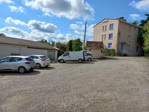 dois carros estacionados num parque de estacionamento ao lado de um edifício em Les Grizzlies-le Mauzac em Limoux