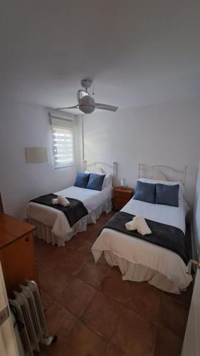 a bedroom with two beds and a ceiling fan at El Madroño de la Encantada in Córdoba