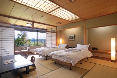 a bedroom with two beds and a table and a window at Itsukushien 