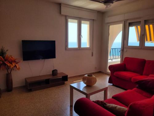 een woonkamer met een rode bank en een tv bij Apartamento con vistas al mar in Villajoyosa