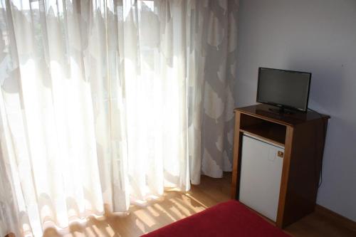 a television sitting on top of a dresser next to a window at Hotel Classis in Bragança