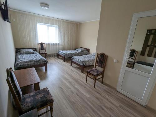 een kamer met drie bedden en een tafel en stoelen bij Гостиный дом 
