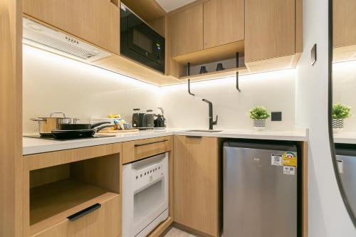 a small kitchen with wooden cabinets and a dishwasher at The SACHA Apart-Hotel Thonglor in Bangkok