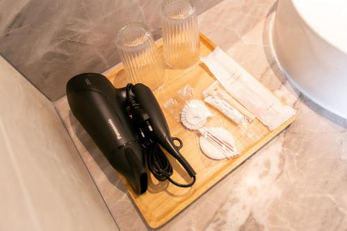 a black hair dryer on a wooden tray next to glasses at The SACHA Apart-Hotel Thonglor in Bangkok