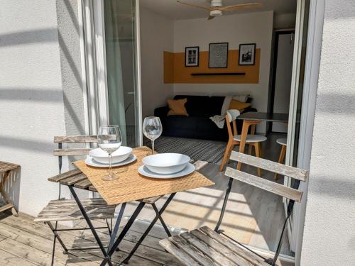 une table avec des verres et des assiettes sur un balcon dans l'établissement La Terrasse du tramway, Parking, 30min de Paris, à Bezons