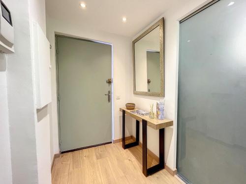 La salle de bains est pourvue d'un lavabo, d'un miroir et d'une porte. dans l'établissement Appartement cosy au centre de Cannes, à Cannes