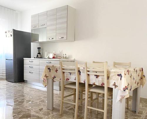Il comprend une cuisine équipée d'une table, de chaises et d'un réfrigérateur. dans l'établissement Le Rose Apartment, à Ortona