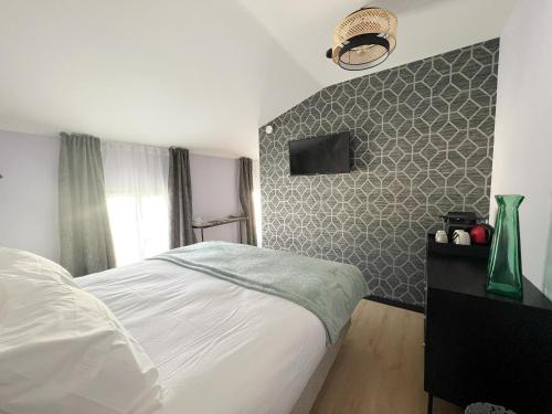 sypialnia z białym łóżkiem i ścianą w obiekcie Le240b #4 w mieście Saint-Mard