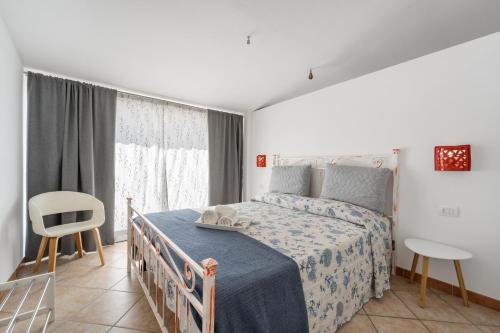 a bedroom with a bed and a chair and a window at Le tenute del mandarino in Elmas