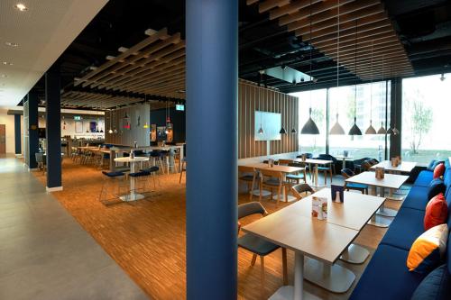 a restaurant with tables and chairs and windows at Holiday Inn Express & Suites - Basel - Allschwil by IHG in Basel