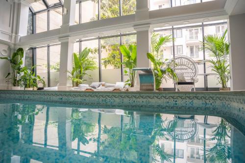 a swimming pool in a house with a large room with windows at Queen's Court Hotel & Residence in Budapest