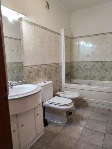 a bathroom with a sink and a toilet and a bath tub at Apartamento acolhedor Oeiras in Barcarena