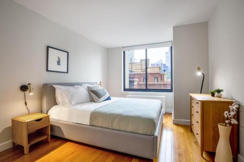 a white bedroom with a bed and a window at Midtown 1BR w Pool Gym Parking nr Times Sq NYC-378 in New York