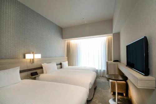 a hotel room with two beds and a flat screen tv at Hotel Keihan Tsukiji Ginza Grande in Tokyo