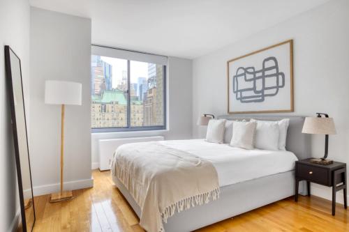 Un dormitorio blanco con una cama grande y una ventana en Midtown 1BR w DM Elevator Gym nr Times Sq NYC-798 en Nueva York