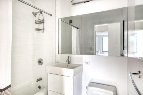 Baño blanco con lavabo y espejo en Midtown 1BR w DM Elevator Gym nr Times Sq NYC-798 en Nueva York