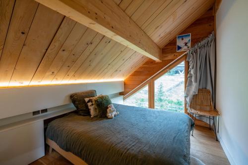 Bett in einem Zimmer mit Holzdecke in der Unterkunft Chalet Orezza in La Salle Les Alpes