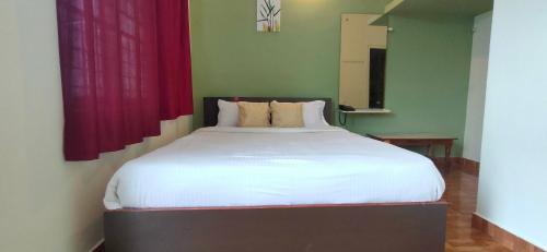 a bedroom with a large white bed with red curtains at Lucky Inn Coorg in Kushālnagar