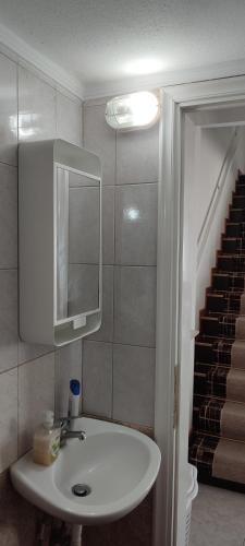 a bathroom with a sink and a mirror and stairs at Marianna's apartment 2 in Nea Moudania
